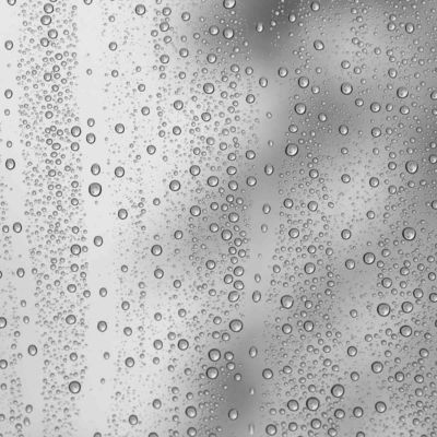 Multiple water drops or raindrops of different sizes on a transparent glass window